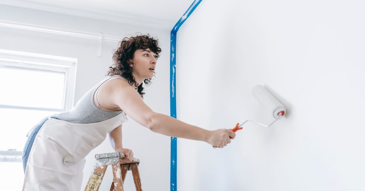 Tradesperson applying an even coat of paint to an interior wall