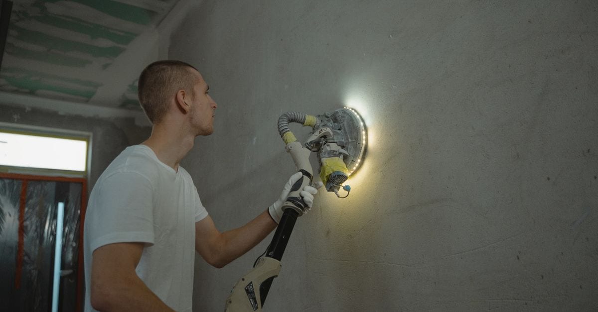Tradesperson preparing an exterior wall surface before painting